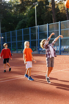 Sporty kids executing basketball jump shots on outdoor court in park