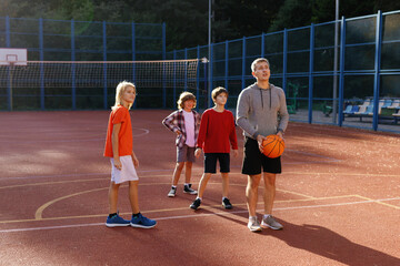 PE teacher teaching pupils how to perform basketball shot on court