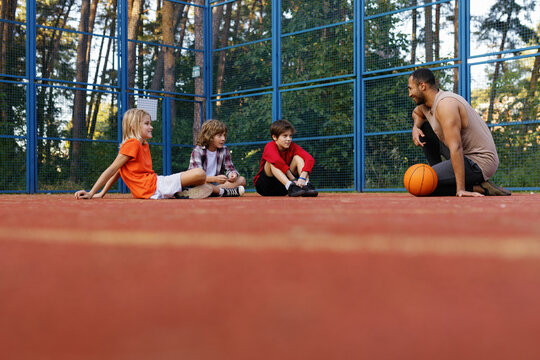 Coach explaining something to pupils on court during basketball lesson