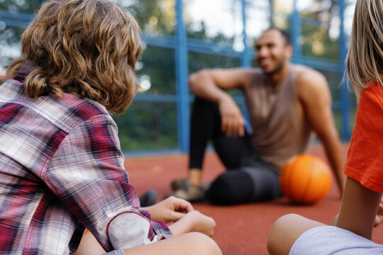 Pupils listening to instructions of PE teacher during basketball class