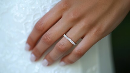 Fototapeta premium A close-up of a hand adorned with a delicate diamond ring, showcasing elegance and beauty against a textured background, likely connected to a wedding or special occasion.