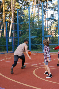 Coach dribbling ball past students on court during basketball game