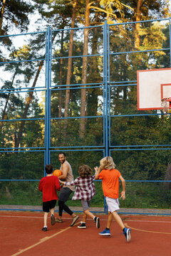 Boys attempting to intercept ball from coach during basketball game