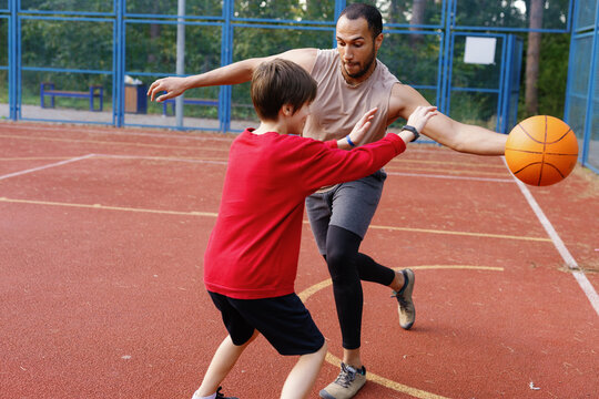 Boy trying to intercept pass of basketball from trainer during game