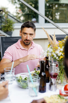 Man telling to partial friends during they having lunch at table
