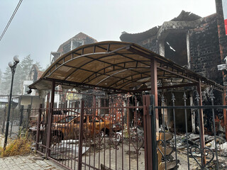 Charred remains of a residential building in Hostomel, Kyiv region, with destroyed vehicles visible...