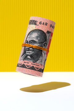 Indian rupee money roll hovering on yelow and white background