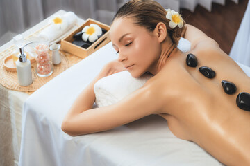 Hot stone massage at spa salon in luxury resort with day light serenity ambient, blissful woman...