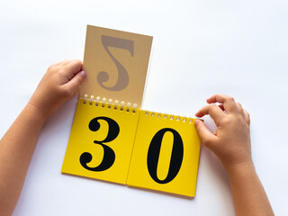 Childs hands flip through yellow pages with numbers on a white background