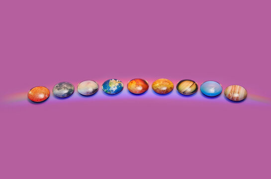  Solar system with rainbow laying in row on purple studio background