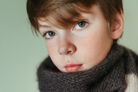 Young boy with expressive eyes wrapped in a scarf