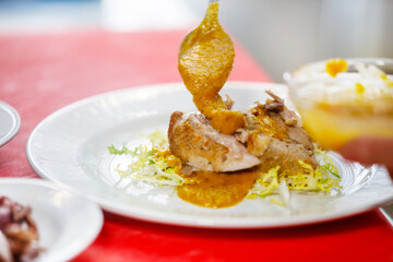 Chef is placing some sauce over quail in a salad