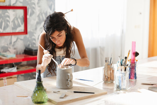 Woman Refining Clay Pitcher in Art Studio