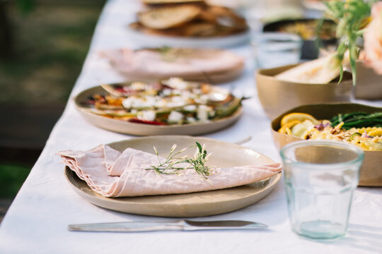 Table setting with plates, napkins, herbs, and foods.