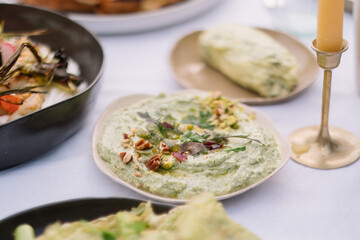Creamy herb dip served with chopped garnishes and nuts.