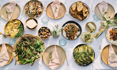 Lavish feast laid on a table with rustic wooden chairs.