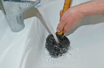 Plunger in men's hands. clearing a clog in the sink with a plunger. plumbing work . cleaning pipes...