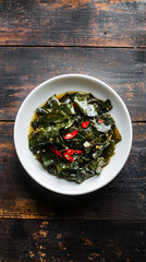 Saut&eacute;ed greens with chili peppers served on a white plate on a vintage wooden table