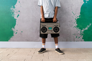 Man holding vintage boombox against graffiti wall