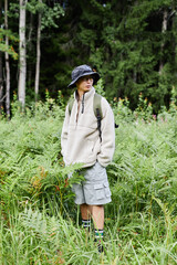 Vertical full length shot of young Asian man as male tourist with backpack and sherpa coat...