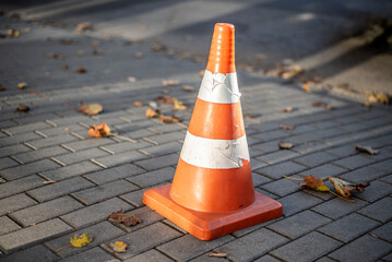 An orange traffic cone on pavement. Urban element