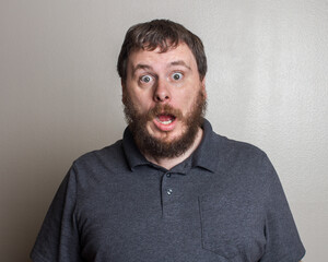 Surprised Bearded Man Expressing Astonishment in Gray Shirt