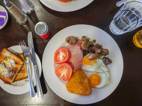 A Hotel Breakfast of eggs, tomato, bacon, mushrooms and hash brown