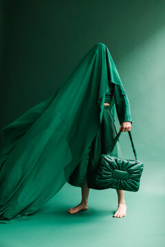 Mysterious Figure Draped in Green Fabric with Stylish Bag