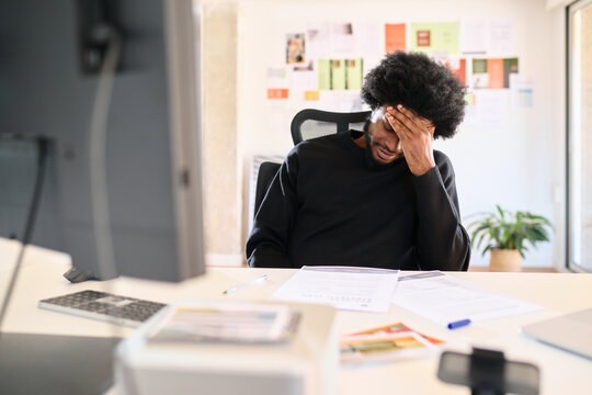 Businessman feeling stressed while working at a desk in a home office
