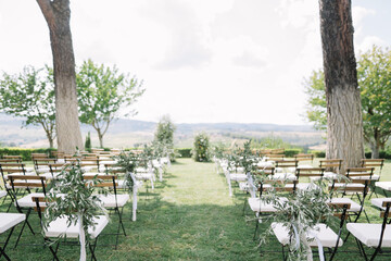 Beautiful outdoor wedding setup with chairs and trees.