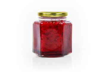 A hexagonal glass jar of homemade red currant berry or cranberry jam sealed with a gold colored...