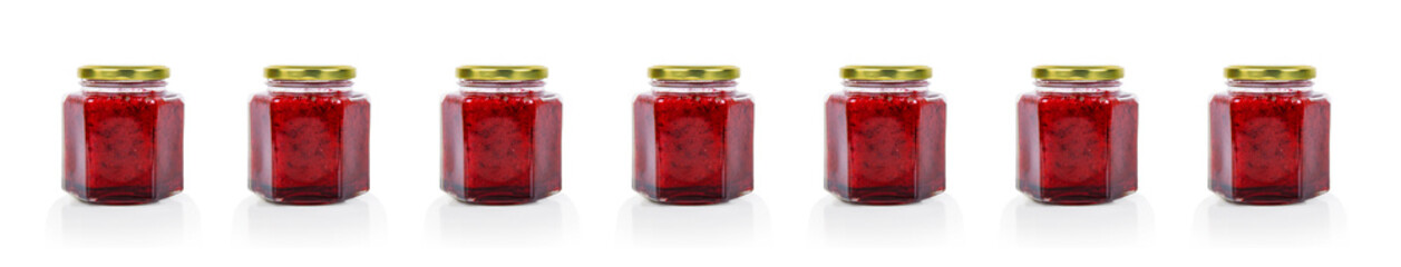 Row of seven hexagonal glass jars of homemade red currant berry or cranberry jam sealed with a gold...