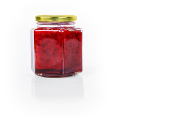 A hexagonal glass jar of homemade red currant berry or cranberry jam sealed with a gold colored...