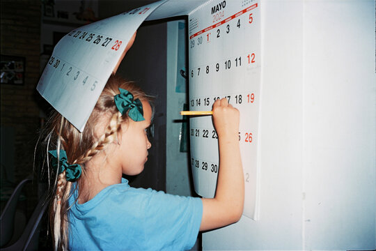 Child marking dates on a wall calendar