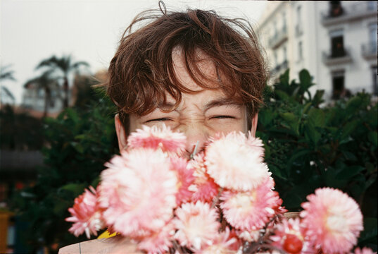Teenager holding pink flowers with squinted eyes