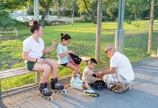 Grandfather Helping Child Prepare For Rollerblading