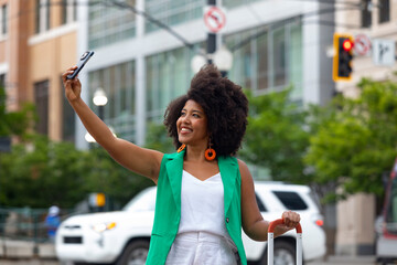 Young black woman taking city  selfie travel photo with suitcase 