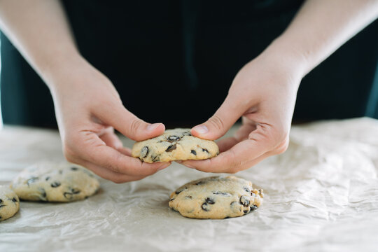 Person examining a fresh-baked chocolate chip cookie.