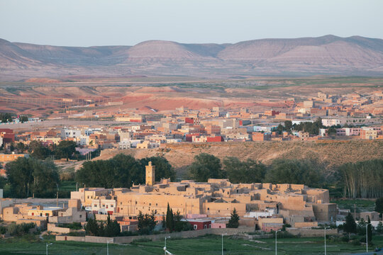 A sprawling town is situated at the base of arid, rolling hills.