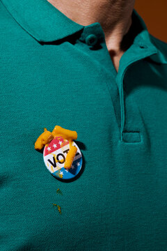 man wearing a vote badge with remains of mac and cheese