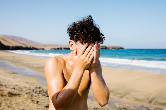 Young tourist smearing his face with sunscreen at a Lanzarote's beach