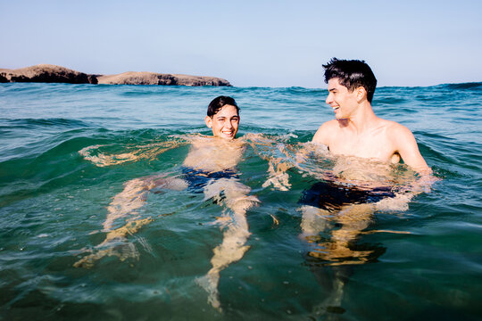 Portrait of teenage brothers immersed in the sea at Papagayo Beach