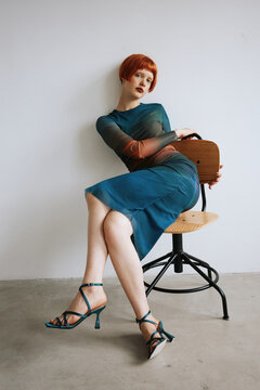 Woman sit on chair in colorful dress and heels