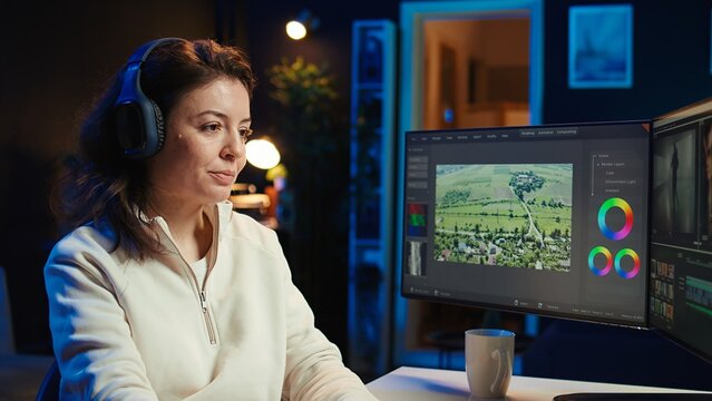 Video editor polishing raw footage, applying modern editing techniques in order to enhance sound and visual quality. Videographer adjusting clips while listening music in headphones, camera B