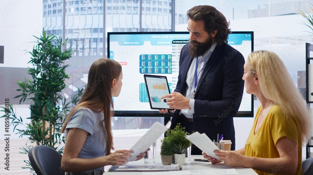 Poster financial adviser presents market analytics to clients using large display and tablet device, teachi