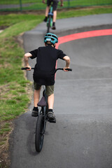 Naklejka premium Boy on a BMX cycling away from camera on bike park. 
