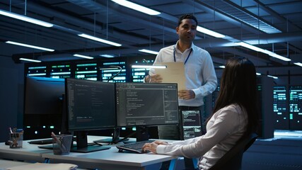 Team of researchers in data center monitoring security threats using PC, implementing cybersecurity...