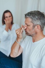 A man sitting in lotus position and a woman practicing alternate nostril breathing exercises during...