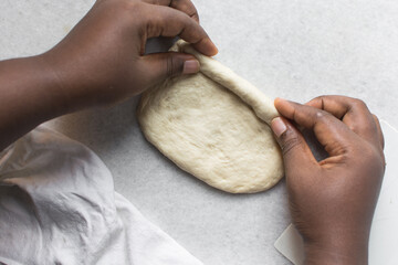 Overhead view of challah dough being shaped on a white granite countertop, top view of homemade...