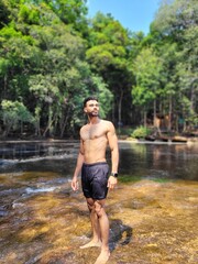 Young Man Posing Near a Waterfall in a Scenic Natural Setting with Trees and Fresh Air